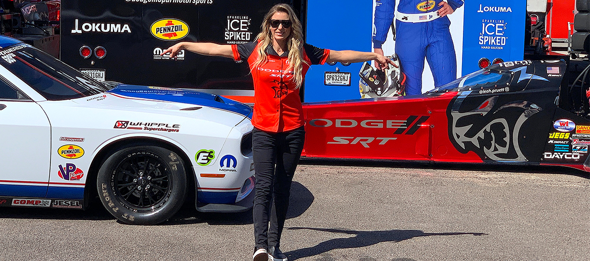 Leah Pruett standing in front of her Drag Pak and Top Fuel Dragster