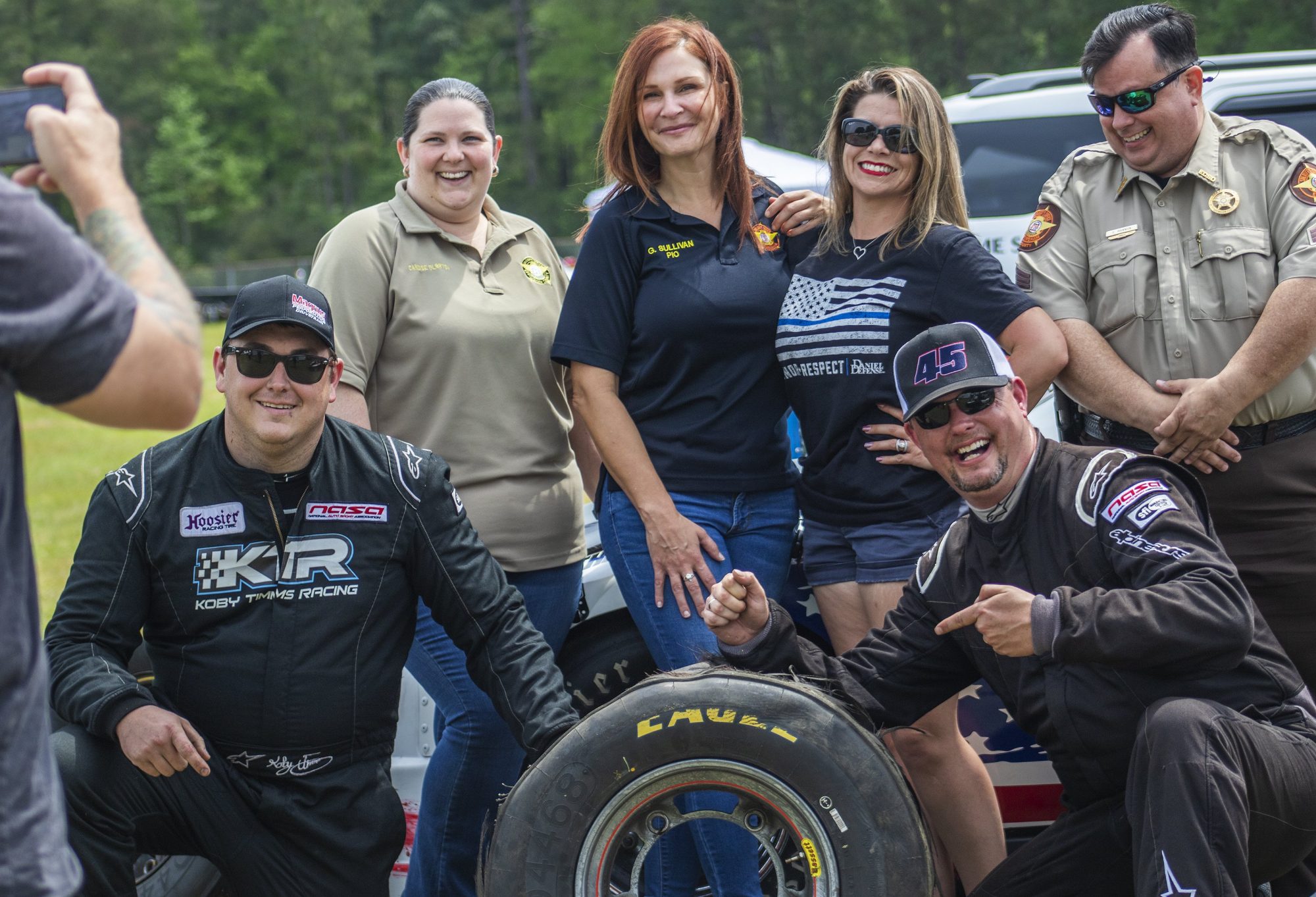 Group of people posing with blown out tire