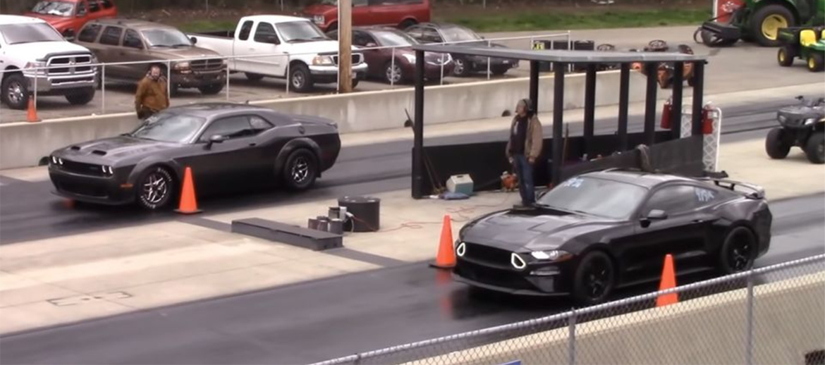 Ford Mustang GT and a Dodge Challenger SRT Hellcat Redeye on the starting line of a drag strip