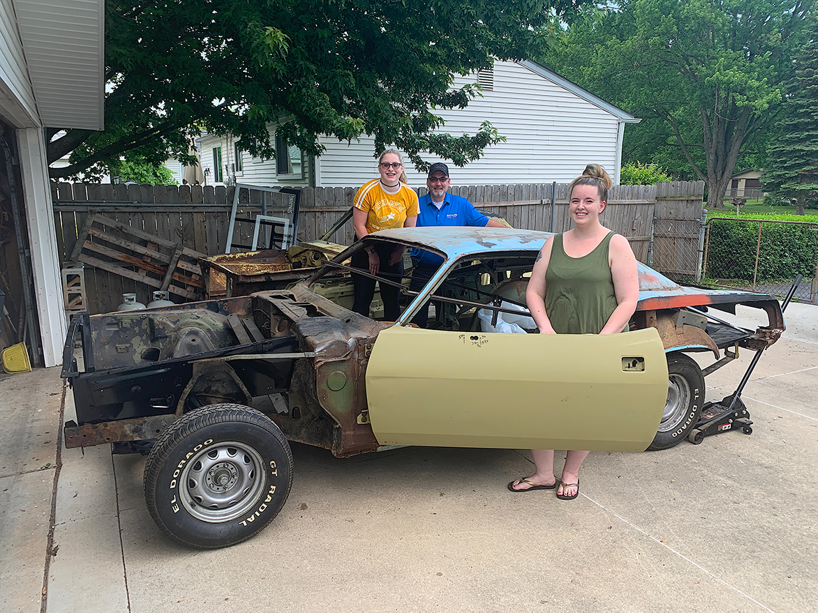 One man and two women with an old vehicle