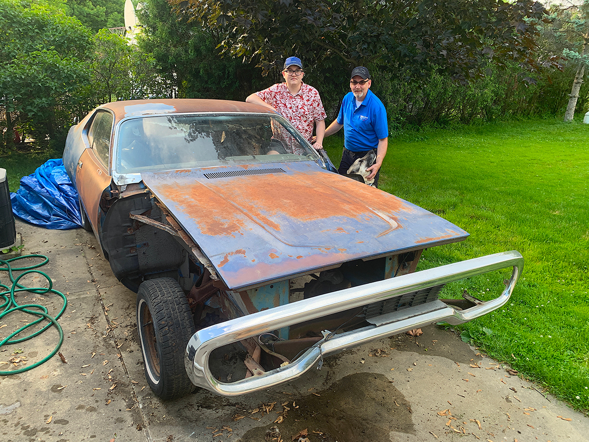 Two men with a rusted vehicle