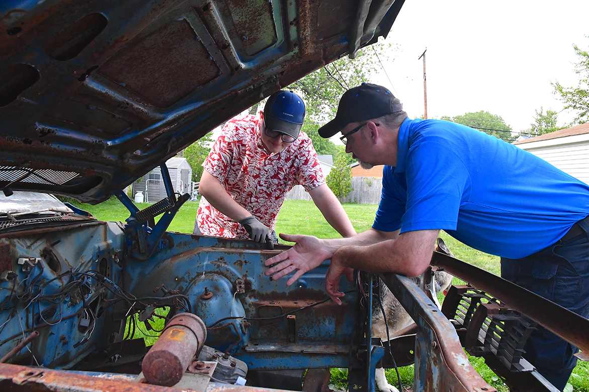 Two men looking inside an old vehicle