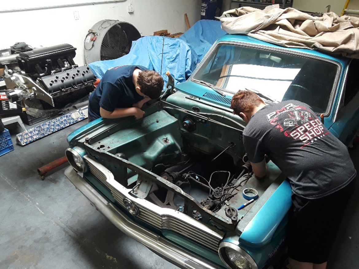 Two kids working on a vehicle engine