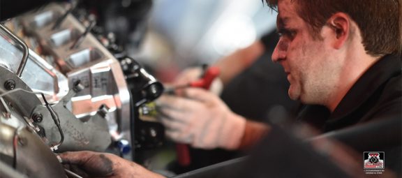 Man with oil on his face working on a vehicle engine