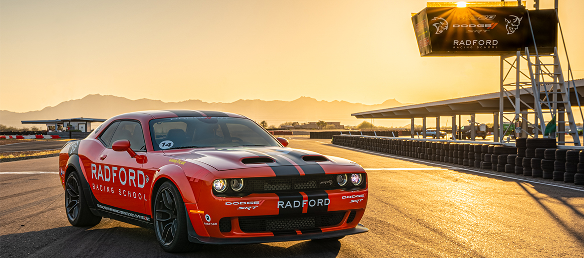 Dodge Challenger parked under a Radford Racing School sign