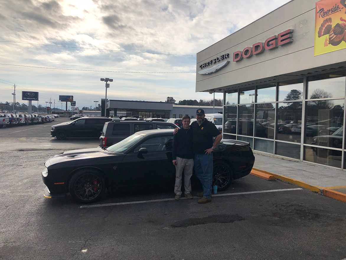 Two men with a Dodge Challenger at a dealership