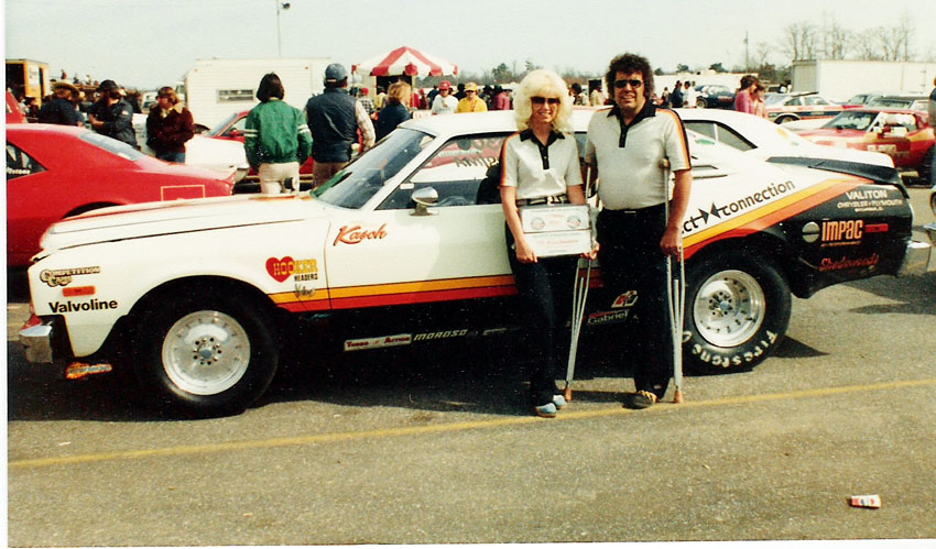 Man and woman standing in front of a drag car