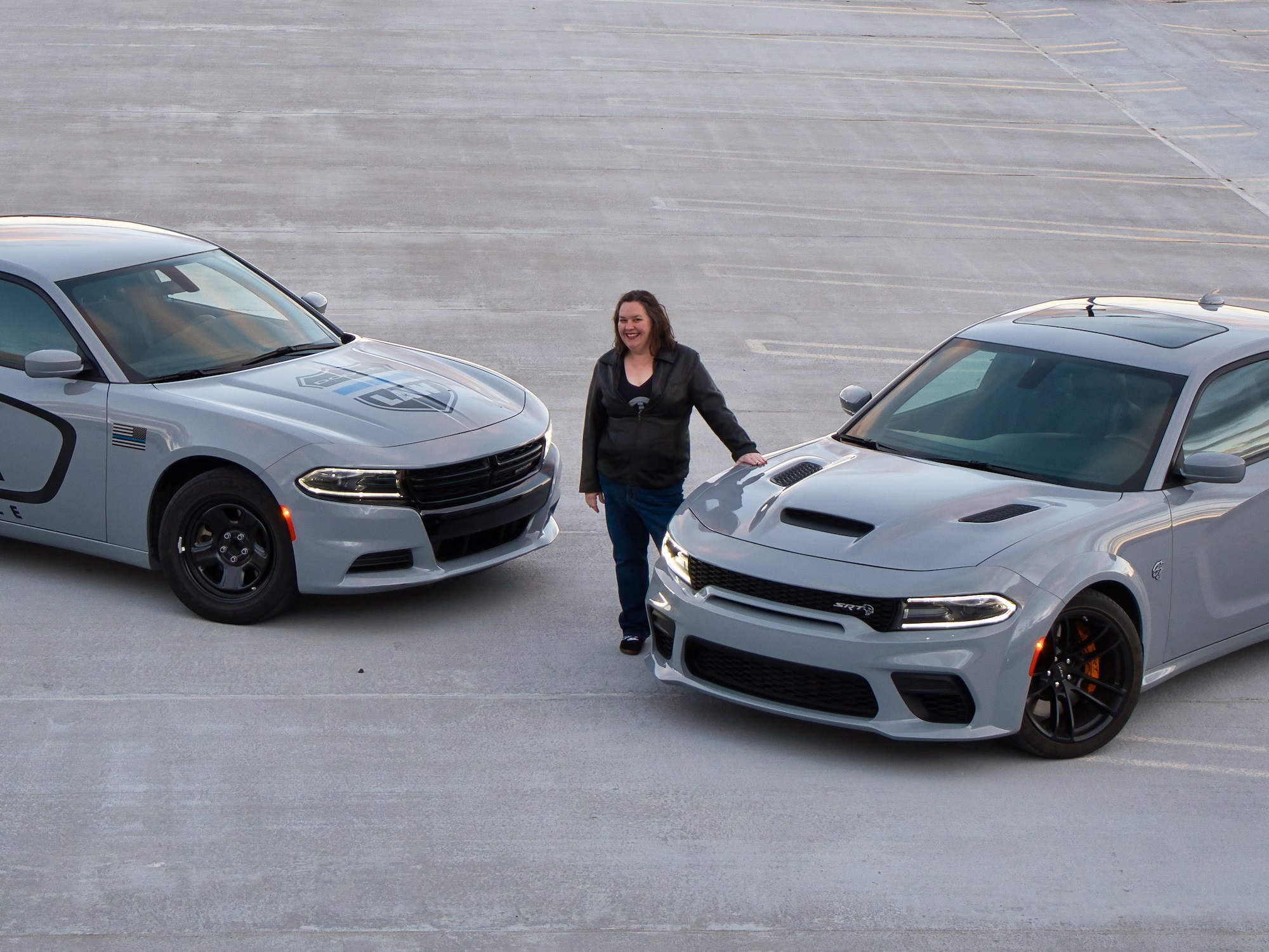 Woman standing next to 2 Dodge Chargers