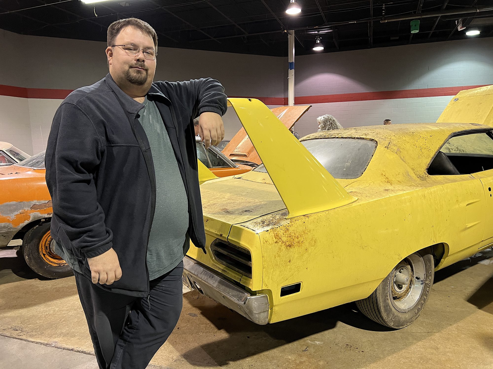 Man standing next to vintage Plymouth vehicle