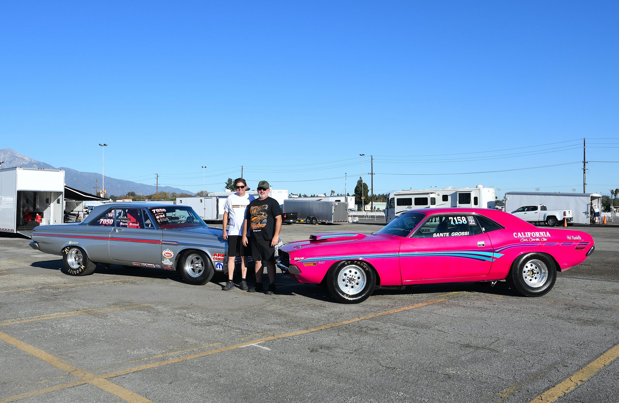 Two men standing next to their race cars