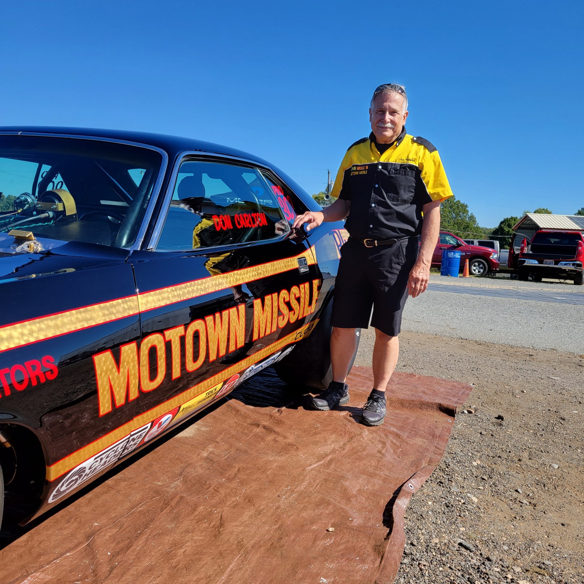 Man posing next to a race car
