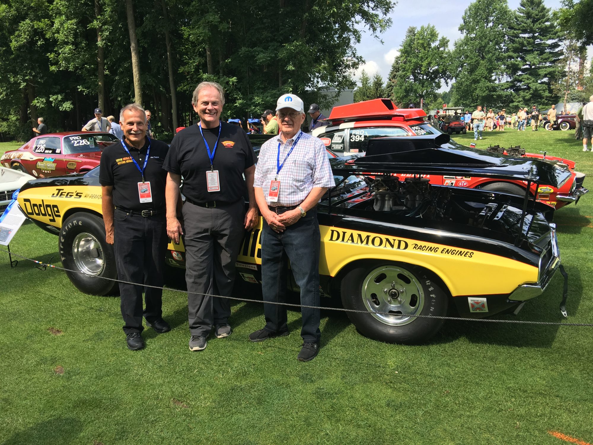 Three men posing next to a race car