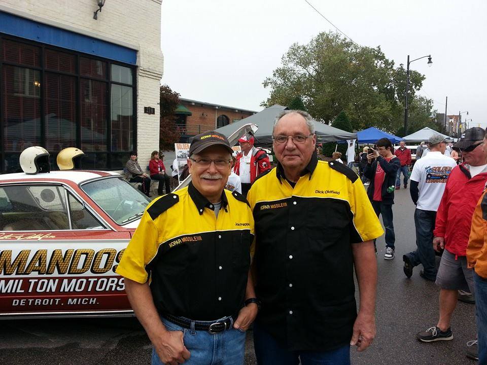 Two men posing next to a race car