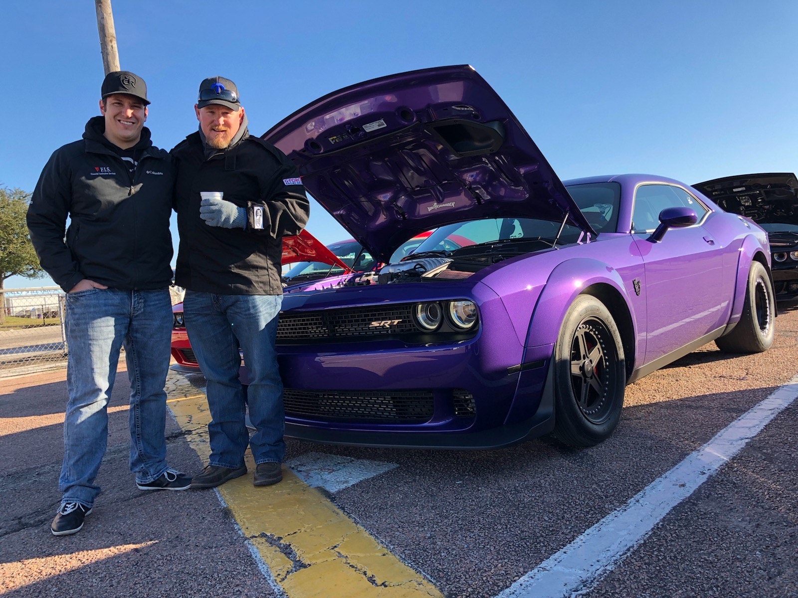 Two men standing in front of a Challenger