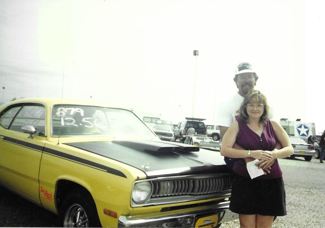 man and woman standing in front of vintage Dodge car
