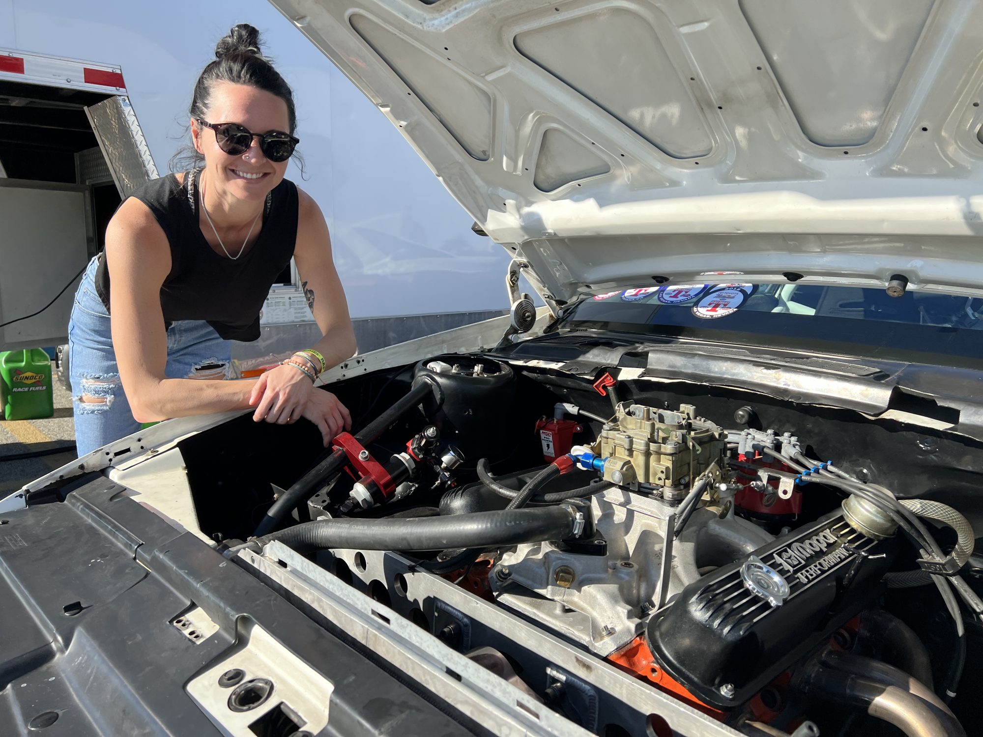 Woman looking under the hood of a race car