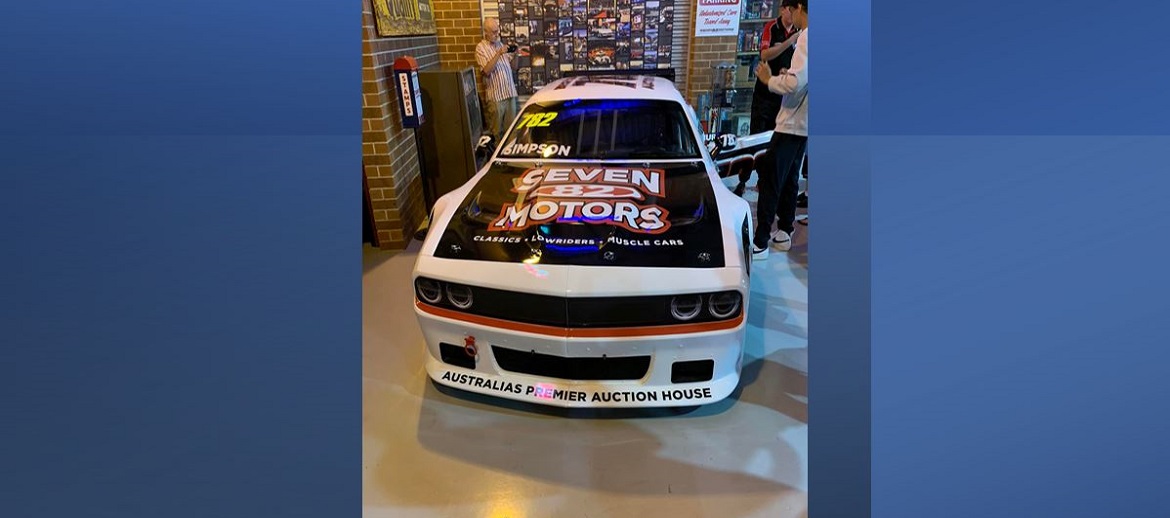 Dodge Challenger with seven 82 motors custom hood in a shop