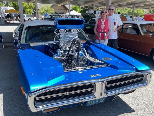 A couple standing next to a vintage Mopar vehicle