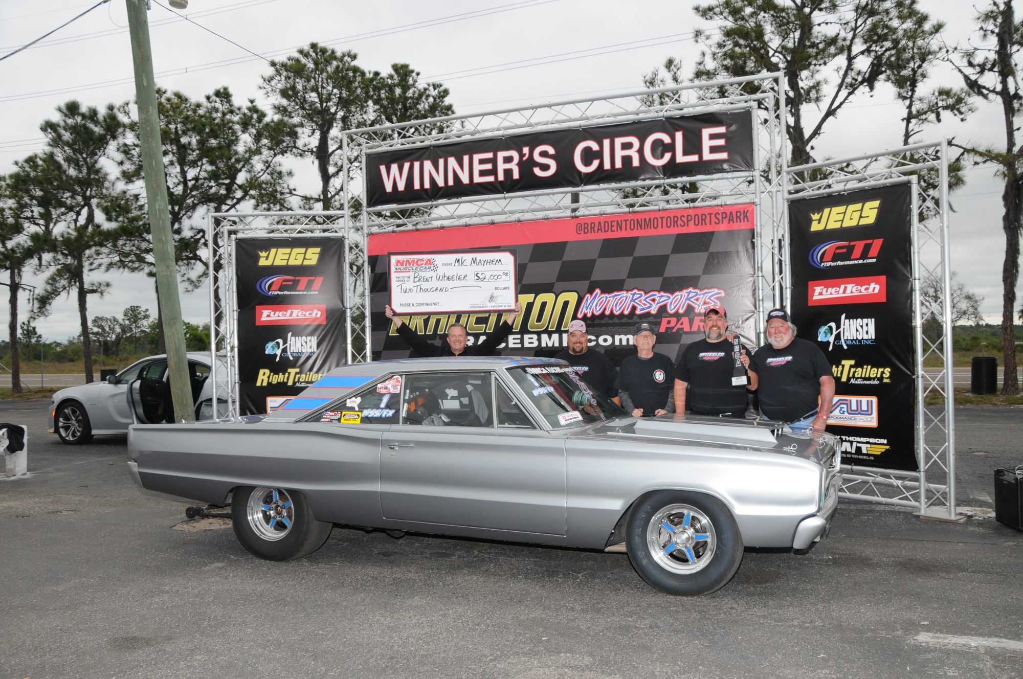 man standing next to his car in the winners circle